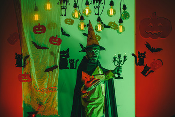 Happy father on halloween background with magik book. Man pronounces a spell, reads a magic book. Man Horror faces. Happy halloween. Horror faces. People wearing hallowwen carnival costumes.