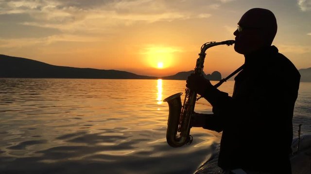 Saxophonist plays on a floating yacht against the backdrop of the sunset