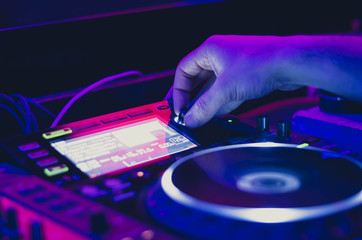 Dj man mixing song on the stage at the club. Close up on hand