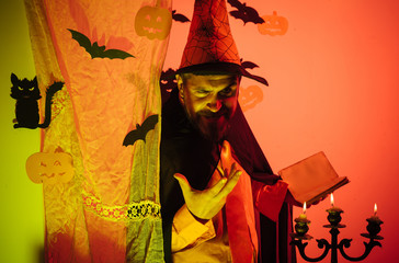 Happy father on halloween background with magik book. Man pronounces a spell, reads a magic book....