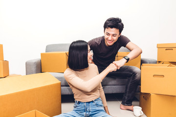 Happy young couple giving high-five and unpacking box and moving into their new home.House moving and real estate concept