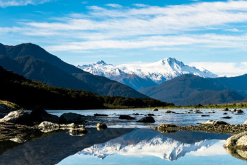 Stunning landscpae of the reflection of the snow mountain on the river. Blue sky and some cloudy.