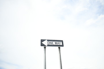 A one way street sign points the way to another place! Maybe heaven, maybe hell, or maybe just another street surrounded by white clouds and a blue sky trying to break through.