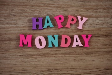 colorful happy monday alphabet letters on wooden background