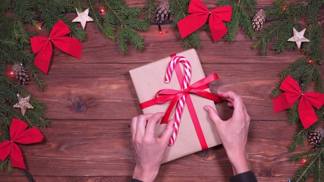 Hands placing festive Christmas gift box on wooden background