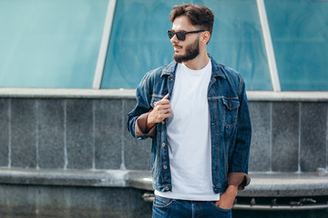 A stylish man with a beard in glasses with a white T-shirt. Street photo