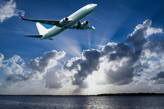 Aircraft in flight with cumulonimbus cloud in blue sky. Australia.