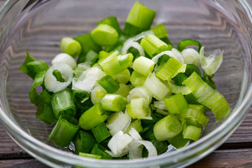 Chopped green onions in a small bowl on the kitchen counter waiting for the chef to use it as a garnish.