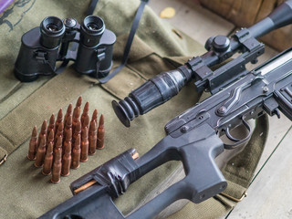 Obraz premium Sniper rifle, binoculars and ammunition on the wooden floor