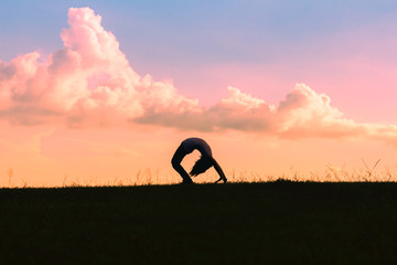 silhouette of children playing yoga on meadow at sunset time