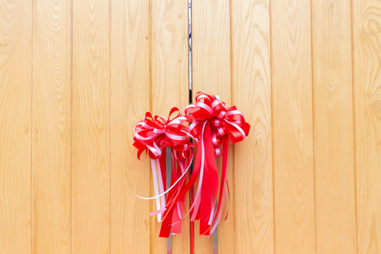 fornt view of wooden gate with red ribbon satin bows.