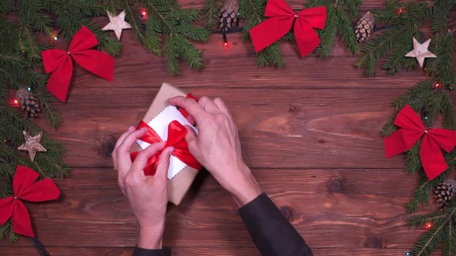 Hands placing cute greeting card on Christmas gift box