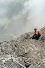 two young attractive female mountain climbers on a steep and exposed Via Ferrata in Alta Badia in...