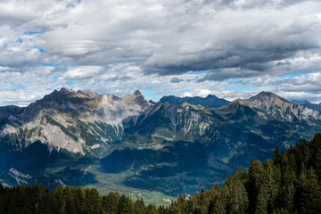 Plakat mountain landscape in the Swiss Alps above Maienfeld with many peaks and forests and valleys below in early autumn 