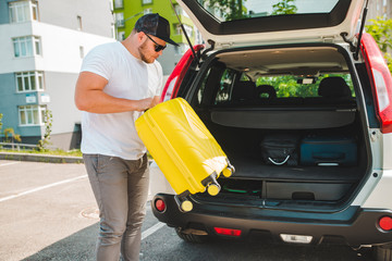 Fototapeta premium man putting bags in car trunk. ready for car travel