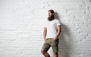 Trendy young bearded man against white brick wall