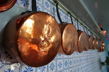 Set de vieilles casseroles en cuivre suspendues au mur d’une cuisine