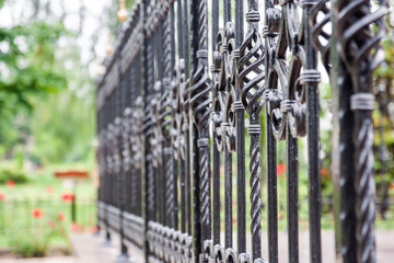 Forged metal fence on green background. Closeup, selective focus