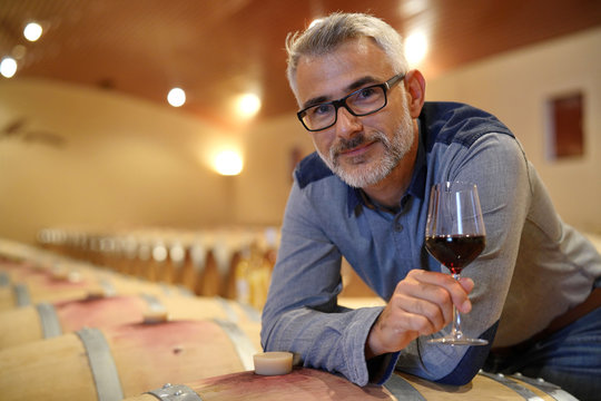 Winemaker tasting red wine in cellar