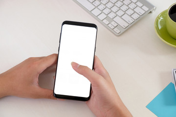 Closeup female using smartphone and blank screen on workspace.