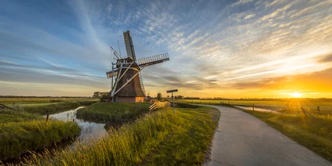 Foto op Canvas Houten windmolen met fietspad bij zonsondergang © creativenature.nl