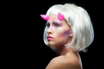 Halloween. Portrait of young beautiful girl with make-up. With white hair and pink devil horns. Isolated on black background.