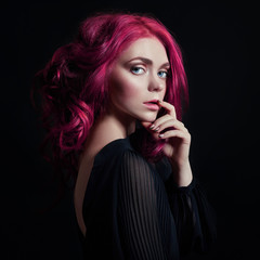 Fototapeta premium Portrait of a woman with bright colored flying hair, all shades of pink. Hair coloring, beautiful lips and makeup. Hair fluttering in the wind. Sexy girl with short hair. Professional coloring