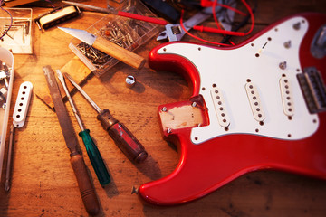 Red electric guitar body on guitar repair desk or in a repair work shop. Neck and pickguard...