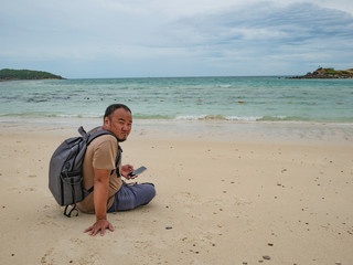 Asian fat backpacker Sitting on the idyllic beach with beautiful Sky in vacation time.Samae San Island thailand.Summer concept.