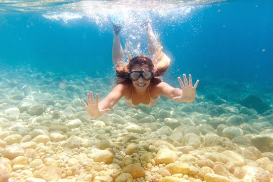 Smiling woman snorkeling in clear water, underwater tropical sea