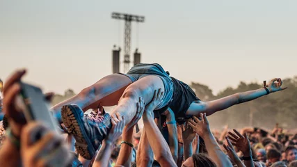 Fototapeten Crowd surfing - audience carry the young woman on their hands during rock concert. © Dziurek