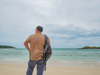 Asian fat backpacker stand while Use mobile phone  on the idyllic beach with beautiful Sky in vacation time.Samae San Island thailand.Summer concept.