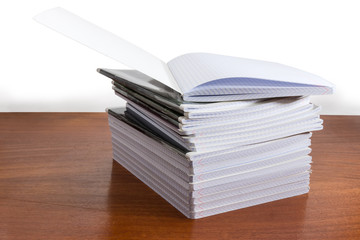 Open exercise book on stack of other exercise books