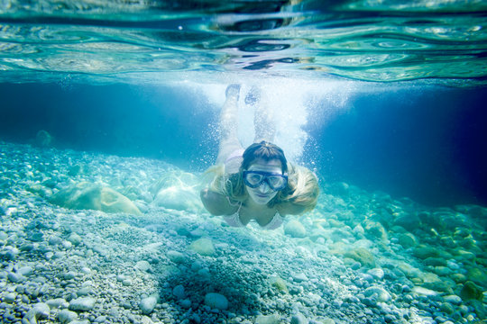Snorkeling in the tropical sea, woman with mask diving underwater
