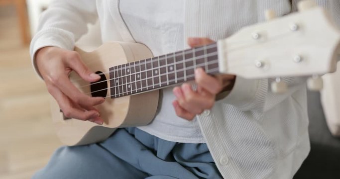 Woman play a song ukulele at home