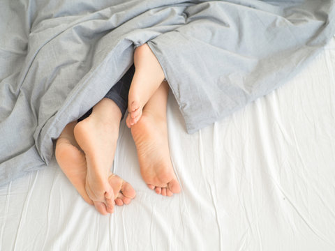 Feet of couple side by side in bed. Morning