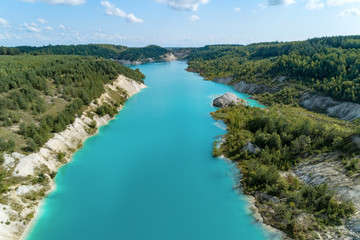 An old gypsum quarry filled with blue and pure water. Aerial view, from top to bottom