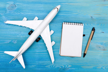 Toy airplane and blank page notepad on the blue wooden table background.