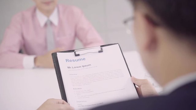 Slow motion - Attractive young Asian businessman in a job interview with corporate personnel manager who reading his CV. Asia businessman talking to male candidate at desk, interviewing job applicant. - Powered by Adobe