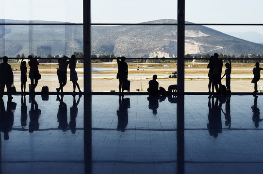 Silhouettes of people near a window in the airport of the city of Bodrum. Turkey. Waiting for the flight home after a rest at the resort.