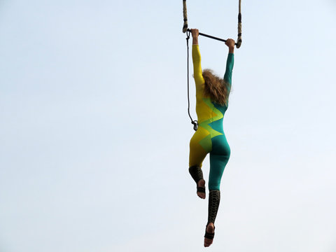 Woman Aerial Acrobat Hanging On Trapeze. Girl Gymnast During A Circus Performance