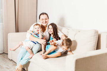 Fototapeta premium Woman with her little kids on the sofa