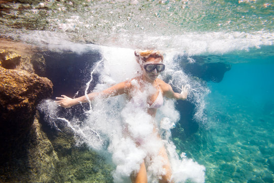 Young woman jumping to water, underwater image