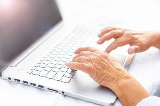 hands of an old woman on the keyboard, grandmother at the laptop, the development of technology
