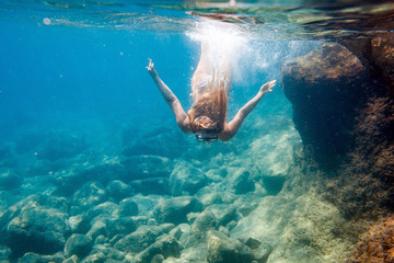 Young woman snorkeling underwater in the clear tropical water