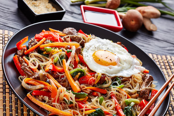 Japchae korean dish in a black plate, close up
