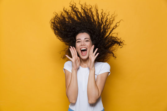 Photo of caucasian woman 20s laughing and having fun with shaking hair, isolated over yellow background