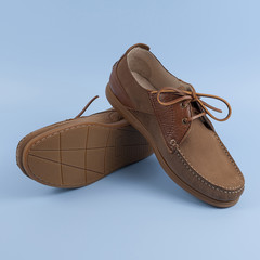 Men's brown moccasins, loafers isolated on blue background.