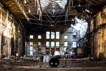 Fototapeta na wymiar A white drum set stands in an abandoned hangar, an abandoned red brick plant. devastation, post apocalypse, urbex