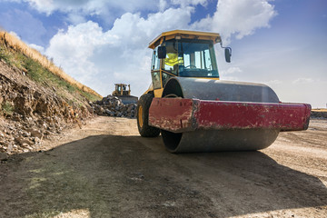 Construction of a road with heavy machinery using a roller and an excavator